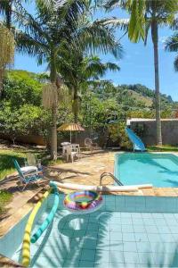 a swimming pool with a slide and palm trees at Chácara do Maurão - tranquility and nature in Serra Negra