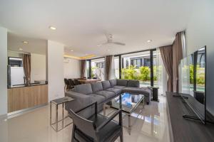 a living room with a couch and a glass table at 5bdr pool villa in Laguna Park 2 in Phuket