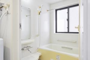 a bathroom with a tub and a toilet and a window at Arcadia Nishikamata in Tokyo