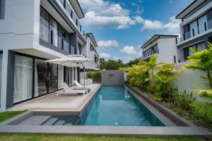 a swimming pool with an umbrella next to a building at 5bdr pool villa in Laguna Park 2 in Phuket