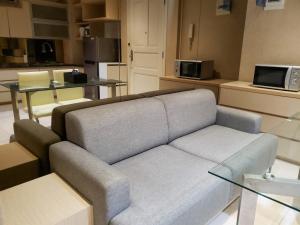 a living room with a couch and a table at Minimalist and Comfy 1BR at The Boulevard Apartment By Travelio in Jakarta