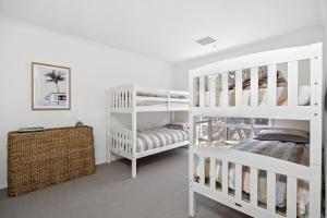 a white bedroom with two bunk beds and a crib at Harlech House Rye in Rye +17 photos