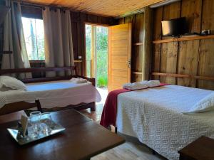 a bedroom with two beds and a table and a tv at Pousada São Miguel in Cunha +94 photos