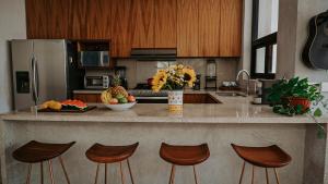 a kitchen with a counter with chairs and a counter top at Casa del Loro 3 BR Luxury Villa with Private Pool in Tulum