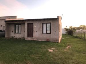 una pequeña casa sentada en un patio junto a un campo en El Cardo, en General Belgrano