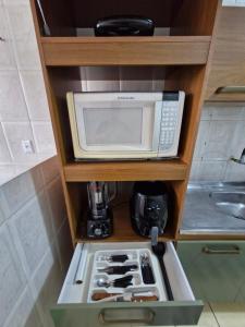 a microwave sitting on a shelf in a kitchen at Apto no Centro de São Leopoldo in São Leopoldo