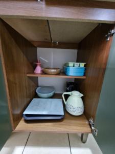 a wooden cabinet with bowls and plates and a tea pot at Apto no Centro de São Leopoldo in São Leopoldo