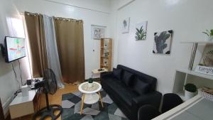 a living room with a black couch and a table at JV Modern 1BR Condo beside SM Marilao, Pool Access, Fast WIFI in Marilao