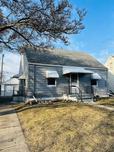a gray house with a porch and a tree at Charming & Spacious 3 bedroom Home near Downtown Ferndale, MI in Ferndale