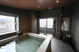 a bathroom with a bath tub with a window at Matsubaya Ryokan in Kyoto