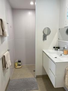 a white bathroom with a sink and a mirror at Beachside retreat in Caloundra