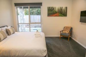 a bedroom with a bed and a chair and a window at Hidden Haven in Bright