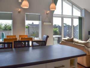 a living room with a table and chairs and windows at Grays Cottage in Sewerby
