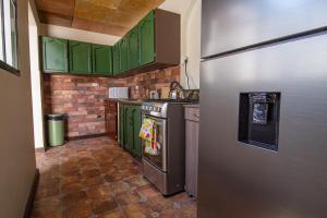 a kitchen with green cabinets and a stainless steel refrigerator at Casa de Helen in Antiguo Cuscatlán