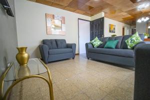 sala de estar con 2 sofás azules y mesa de cristal en Casa de Helen, en Antiguo Cuscatlán