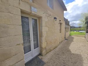 a stone building with a door on the side of it at Gîte Authentique avec Piscine, Cheminée et Étang Privé à Naussannes - Proche Bergerac - FR-1-616-205 in Naussannes