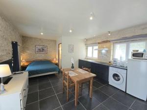 eine Küche und ein Schlafzimmer mit einem Bett und einem Tisch in der Unterkunft Studio cosy avec piscine partagée et étang privé, proche Bergerac et sites touristiques du Périgord - FR-1-616-207 in Naussannes
