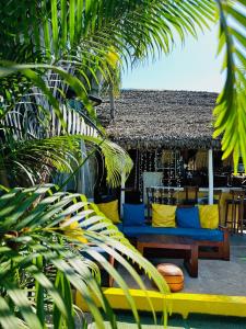 a blue couch with yellow pillows sitting on a patio at Bungalows des tropiques in Nosy Be