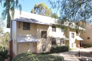 a large white building with trees in the background at Villa 2br Petit Verdot Villa located within Cypress Lakes Resort in Pokolbin