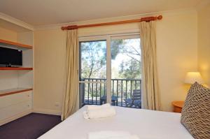 a bedroom with a bed and a window with a balcony at Villa 2br Petit Verdot Villa located within Cypress Lakes Resort in Pokolbin +17 photos