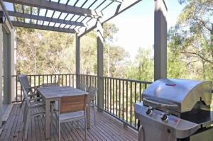 a grill on a deck with a table and chairs at Villa 2br Petit Verdot Villa located within Cypress Lakes Resort in Pokolbin