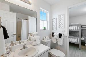 a bathroom with a sink and a toilet and a mirror at White Sand Beachfront Paradise in Gulf Shores +51 photos