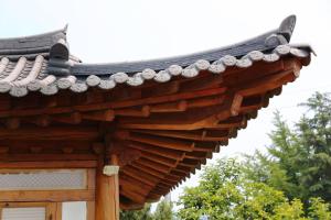 a roof of a wooden building with trees in the background at Pear tree house Hanok in Suncheon