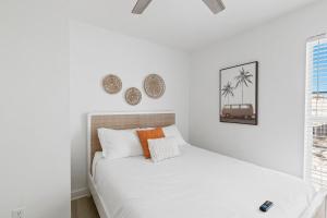 a bedroom with a bed with white sheets and orange pillows at White Sand Beachfront Paradise in Gulf Shores