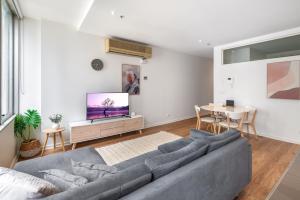 a living room with a couch and a tv at Melbourne CBD 2BR Apt with Pool & Gym Access in Melbourne +8 photos