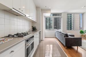 a kitchen with a stove and a couch at Melbourne CBD 2BR Apt with Pool & Gym Access in Melbourne