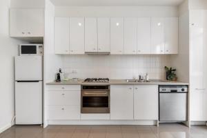 a white kitchen with white cabinets and appliances at Melbourne CBD 2BR Apt with Pool & Gym Access in Melbourne