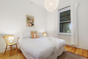 una camera da letto bianca con un letto e una finestra di One Mile Cottage a Beechworth