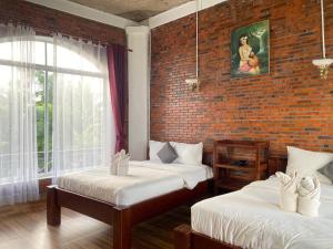 a bedroom with two beds and a brick wall at The Coconut House Hotel in Battambang