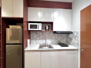a white kitchen with a sink and a microwave at Patsy Place - Mesavirre Garden Residences in Bacolod