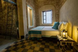a bedroom with a bed and a window and a checkered floor at Dar Ferran in Essaouira
