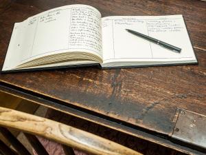 an open book with a pen on a wooden table at Castle House Cottage in Kirkby Stephen
