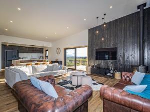 a living room with leather couches and a kitchen at Taylors Alpine Retreat in Ohakune