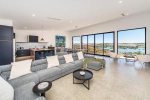 a living room with a gray couch and a kitchen at Riverstone Retreat in Mannum