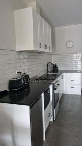 a kitchen with white cabinets and a black counter top at Cooper's Cottages in Lightning Ridge +5 photos