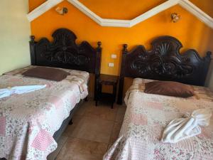 two beds in a room with orange walls at Hotel TINAMIT in San Pedro La Laguna