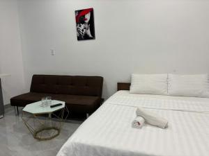 a bedroom with a white bed and a couch at Homestay Villa VINHOMES GRAND PARK QUẬN 9 in Gò Công