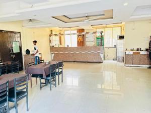 a man standing in a room with tables and chairs at Hotel Mayur Residency in Kalyan