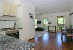 a kitchen with white cabinets and a dining room with a table at Houghs Cabin in Bright