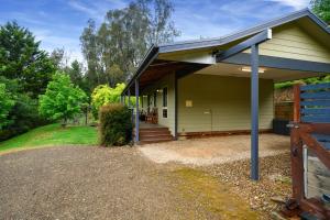 a small yellow house with a porch and a fence at Houghs Cabin in Bright