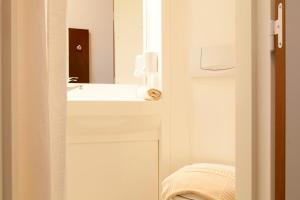 Baño blanco con lavabo y espejo en Pension Stadthalle en Viena