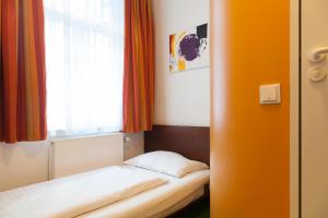 ein kleines Bett in einem Zimmer mit Fenster in der Unterkunft Pension Stadthalle in Wien