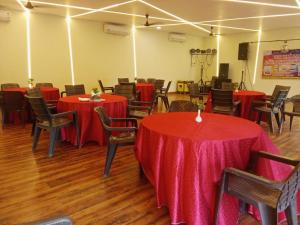 a room with tables and chairs with red table cloths at Kingfisher Resort in Dhanwār