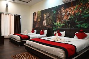 two beds in a room with a painting of a tiger at Kingfisher Resort in Dhanwār +69 photos