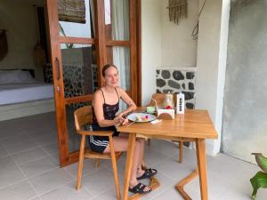 a woman sitting at a table with a plate of food at Cozy bliss homestay sidemen in Sidemen