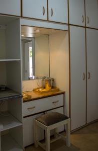 una cucina con armadi bianchi, sgabello e specchio di Tsitsikamma Mountain View Lodge a Stormsrivier